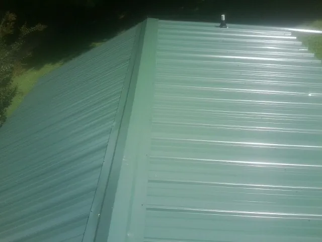 New green metal panels meeting at the ridge of a roof — Flat Roof Repair work by our crew in Cyril