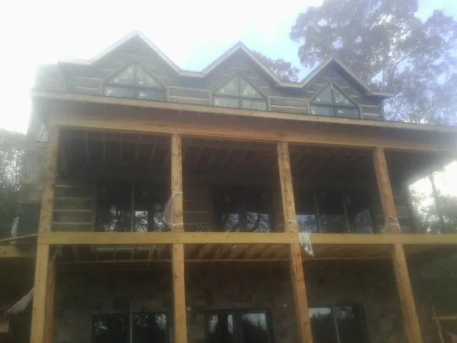 Dormers and porch framing on a large log home under construction — Roof Coating work by our crew in Cyril