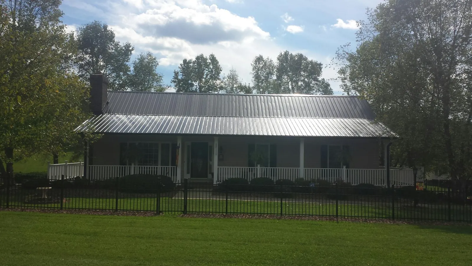 Gray metal roof on a brick ranch with a full width front porch — Gutter Guard Installation work by our crew in Cyril