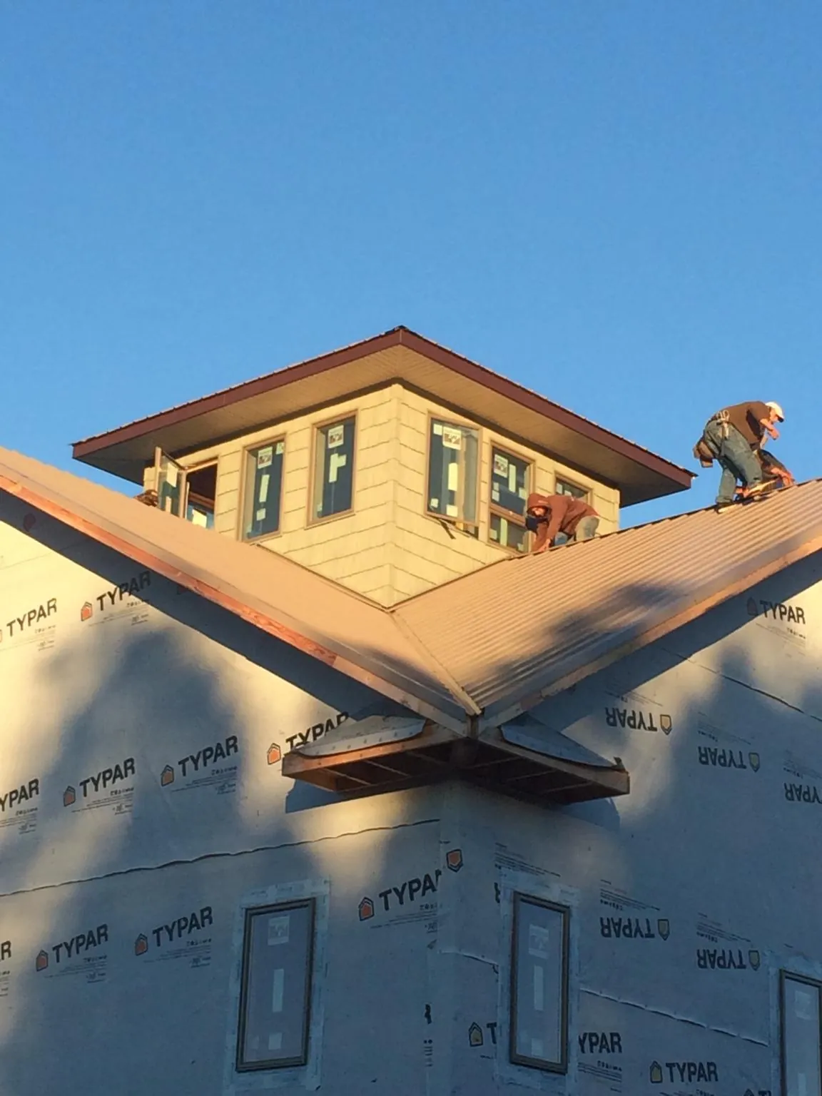 Roofers working around a rooftop cupola on a new metal roof at sunset — Roof Waterproofing in Cyril by Roofing Brothers